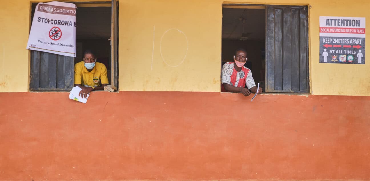 Two men look though windows with covid awareness signs